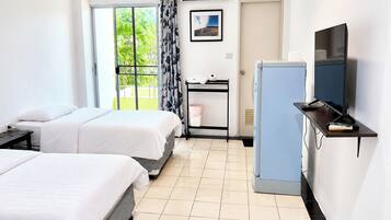 A hotel room with two beds, a desk with a computer, a television, and a window with curtains.