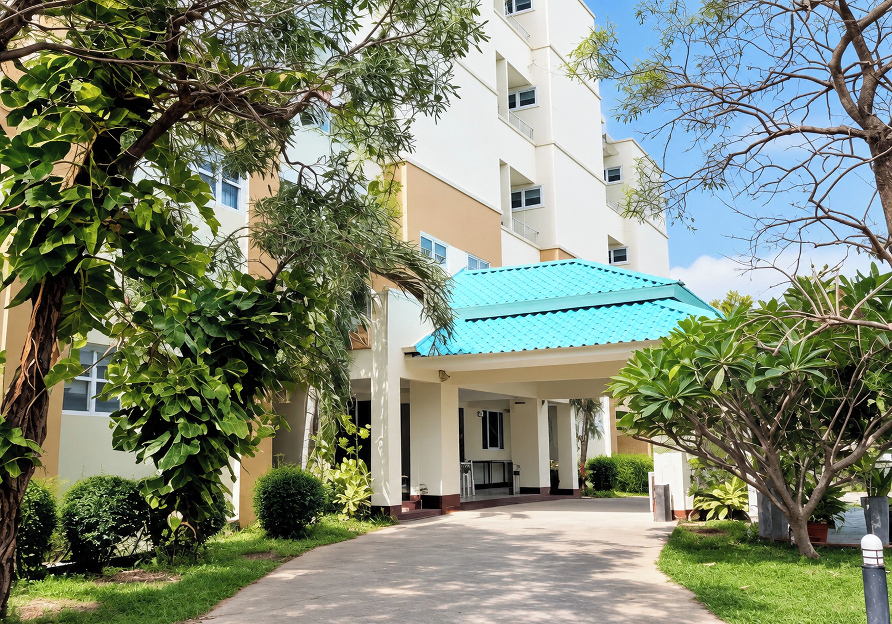 A building with a covered entrance, a pathway leading to it, and surrounding greenery.