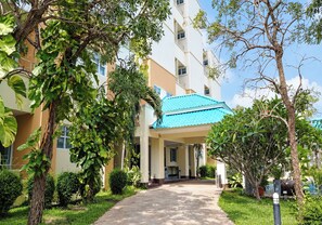 A hotel entrance with a covered walkway, surrounded by greenery and a clear sky. - Udoncabana (Udon Thani)