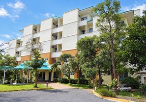 A multi-story hotel with balconies, a covered entrance, and a well-maintained garden. - Udoncabana (Udon Thani)
