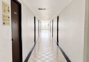 A hotel hallway with doors marked for rooms 401-411, a fire extinguisher, and a tiled floor.