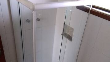 A glass-enclosed shower stall with a white sink and a toilet.