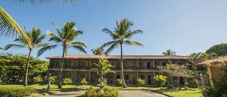 A hotel with a courtyard, palm trees, and a cobblestone path.