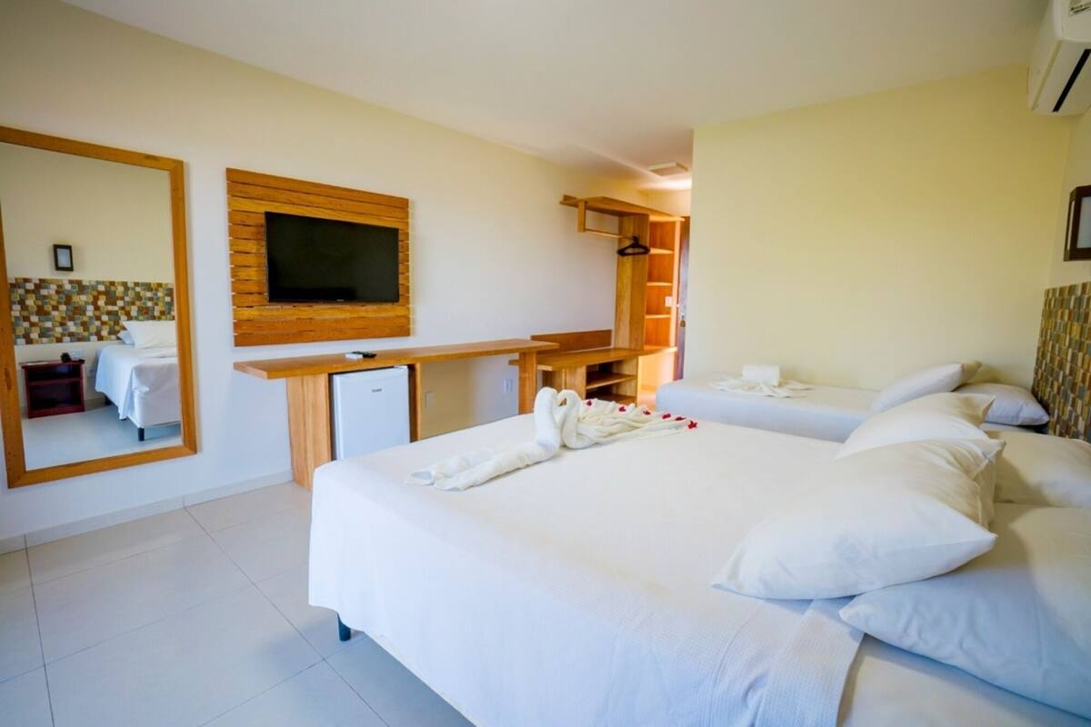A hotel room with a large bed, a desk, a television, and a mirror.