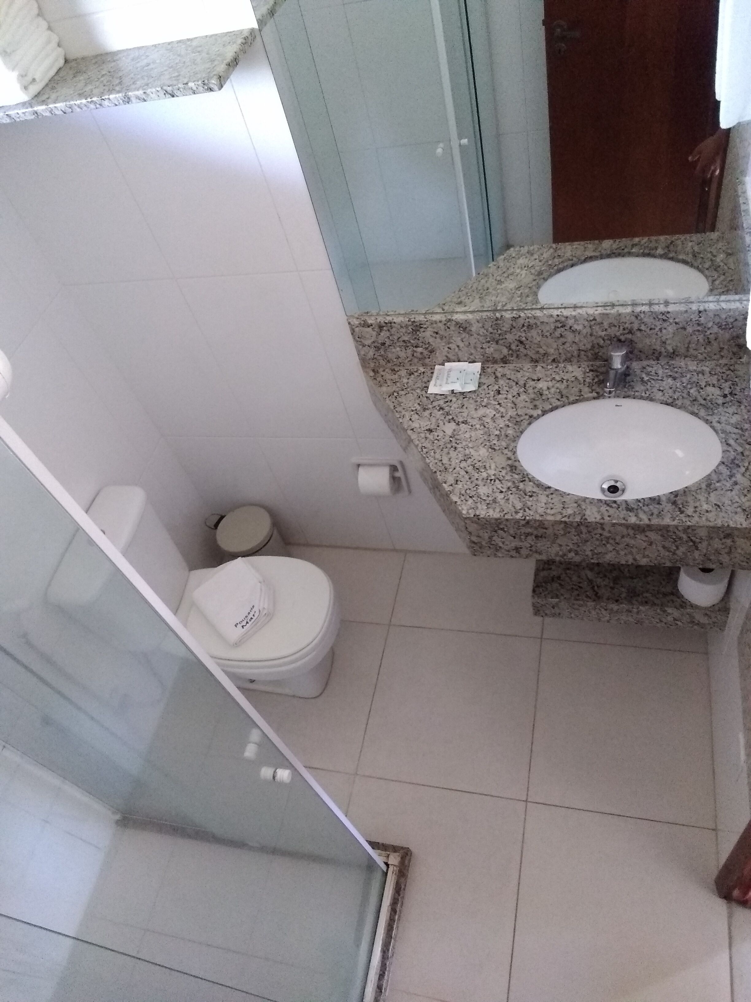 Une salle de bain avec des toilettes blanches, un lavabo en granit et une cabine de douche en verre.
