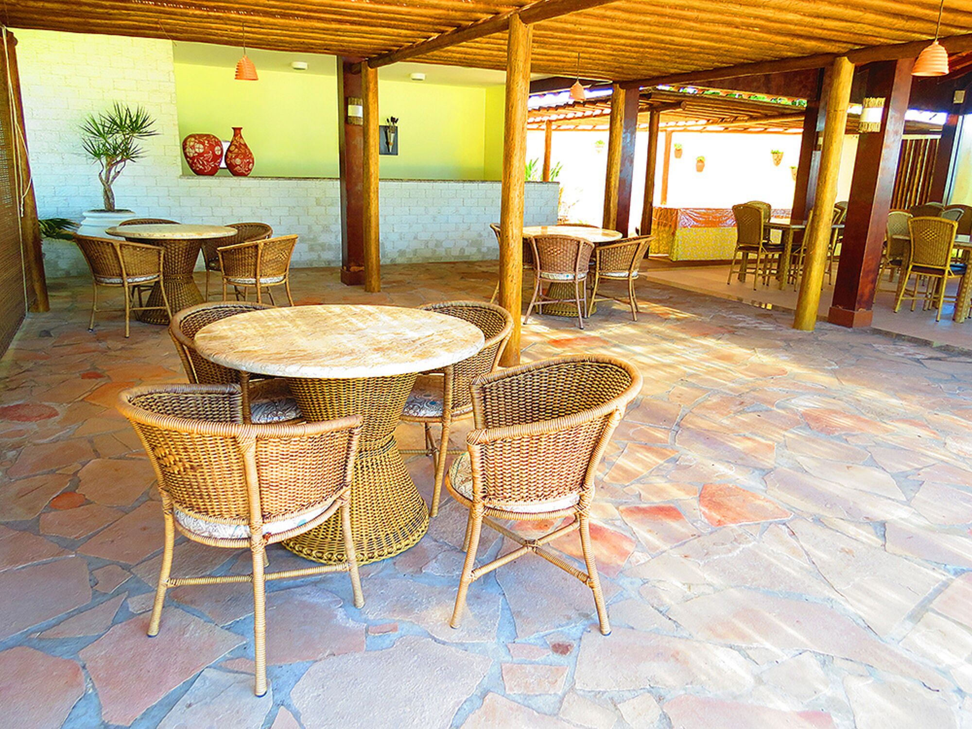 An outdoor patio with wicker furniture and a stone floor.