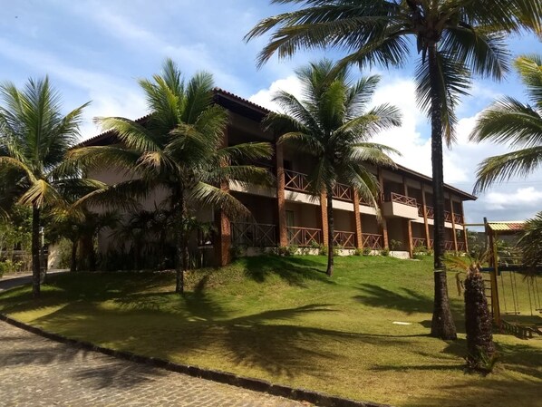 A hotel with a brick facade, multiple balconies, and palm trees. - Pousada do Mar (Ilhéus)