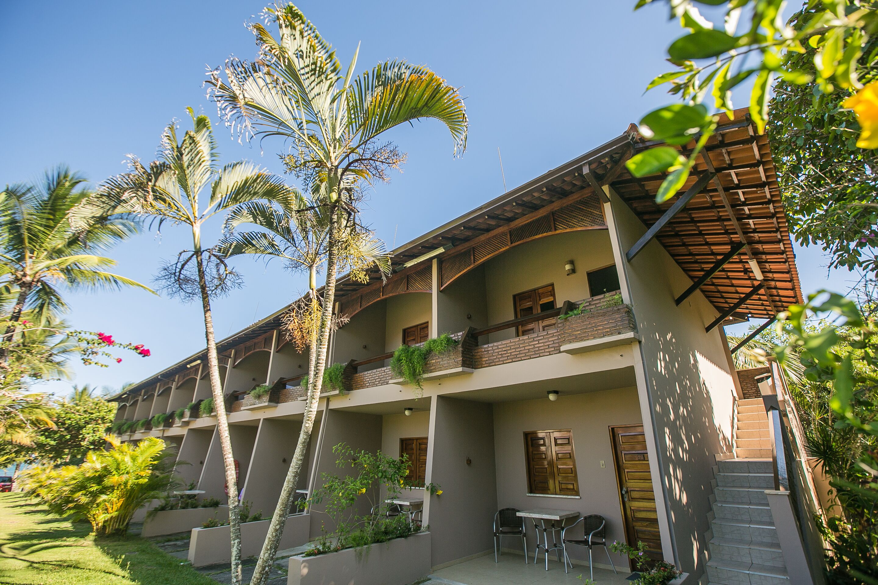 A multi-story hotel with balconies, outdoor seating, and lush landscaping.