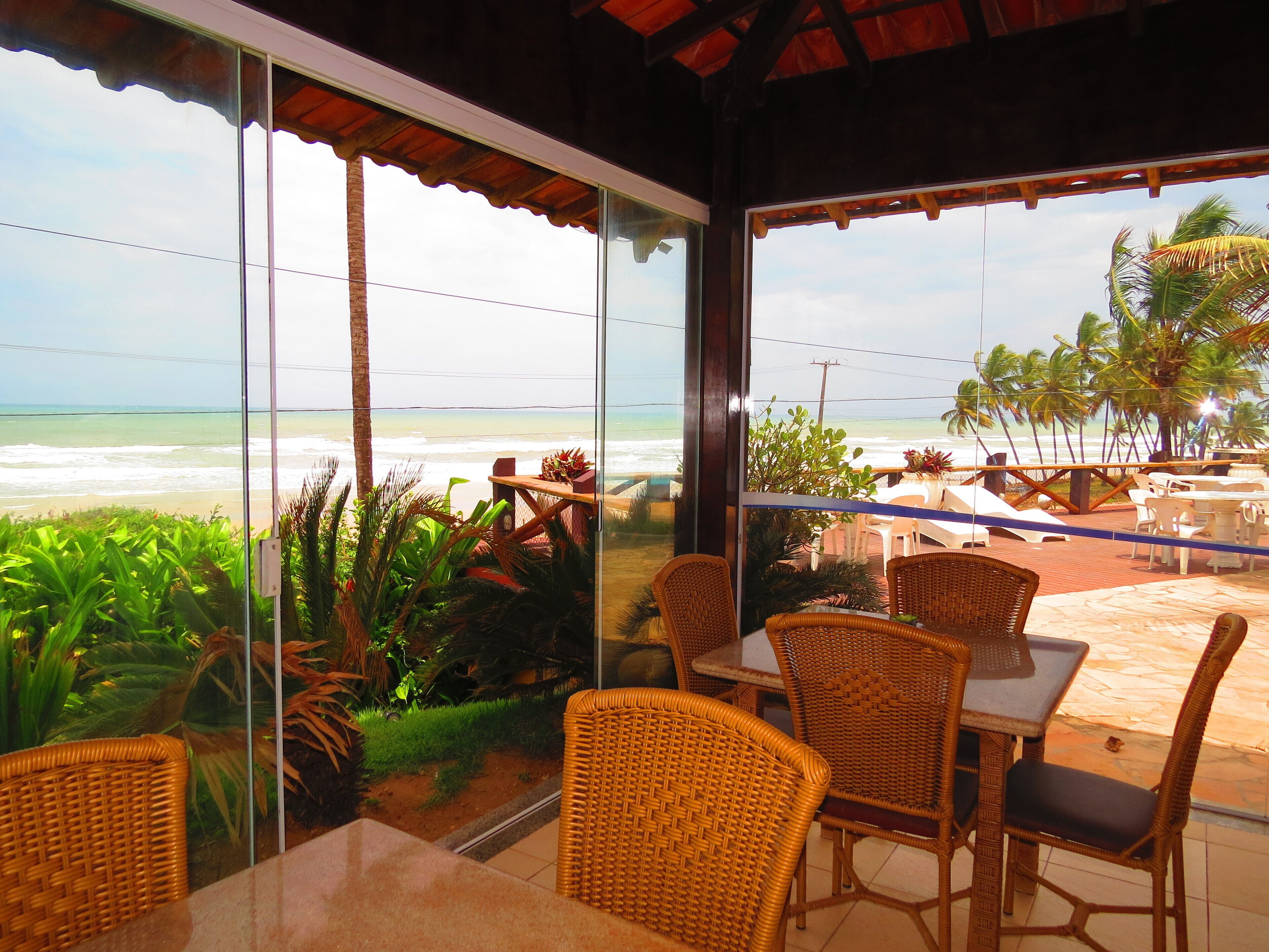 Ein Restaurant direkt am Strand mit Korbmöbeln und Meerblick.