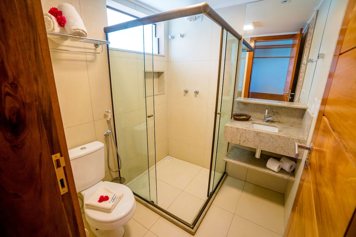 A modern bathroom with a glass-enclosed shower, a toilet, and a vanity with a sink and mirror.
