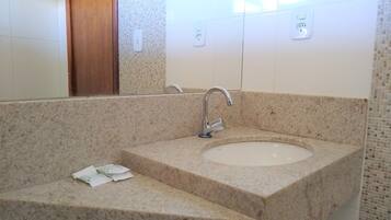 Un baño con lavamanos de encimera de granito, espejo y puerta de madera.