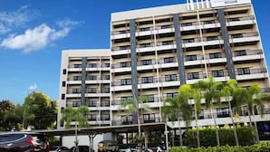 A multi-story hotel with a modern design, featuring balconies on each floor and a covered parking area. - Essential Pattaya (Pattaya)