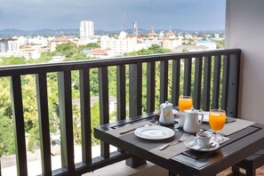 A balcony with a table set for breakfast, including a plate, a cup, a jug of orange juice, and a coffee pot. - Essential Pattaya (Pattaya)