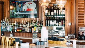 A bar with wooden paneling, a television displaying sports content, and a variety of bottles and glasses on shelves. - Gibson Inn (Apalachicola)