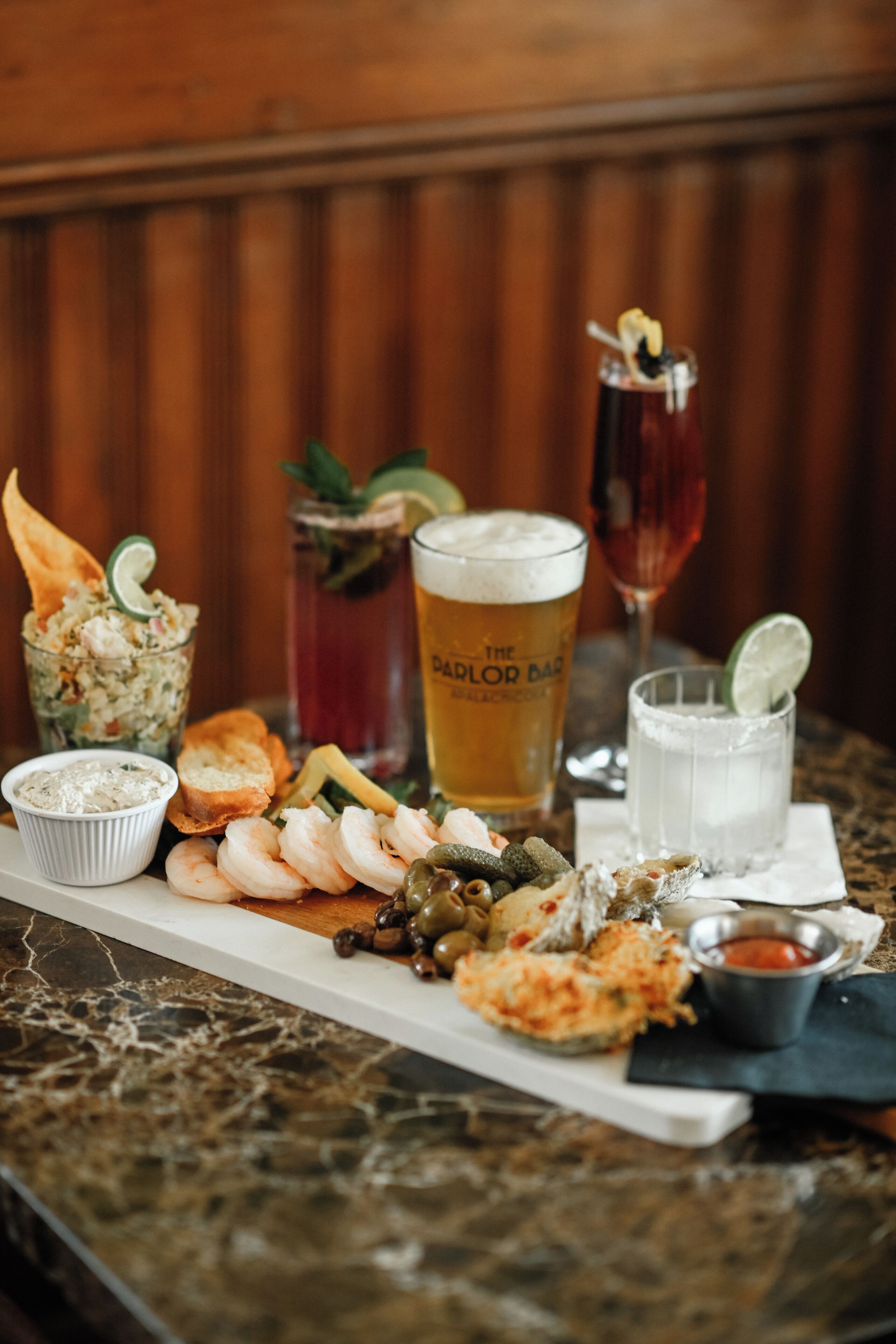 A table with various food items and drinks, including shrimp, bread, and a glass of beer.