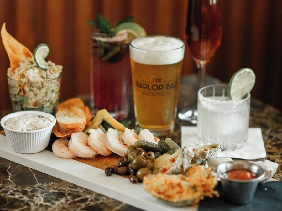 A table with various food items and drinks, including shrimp, bread, and a glass of beer.