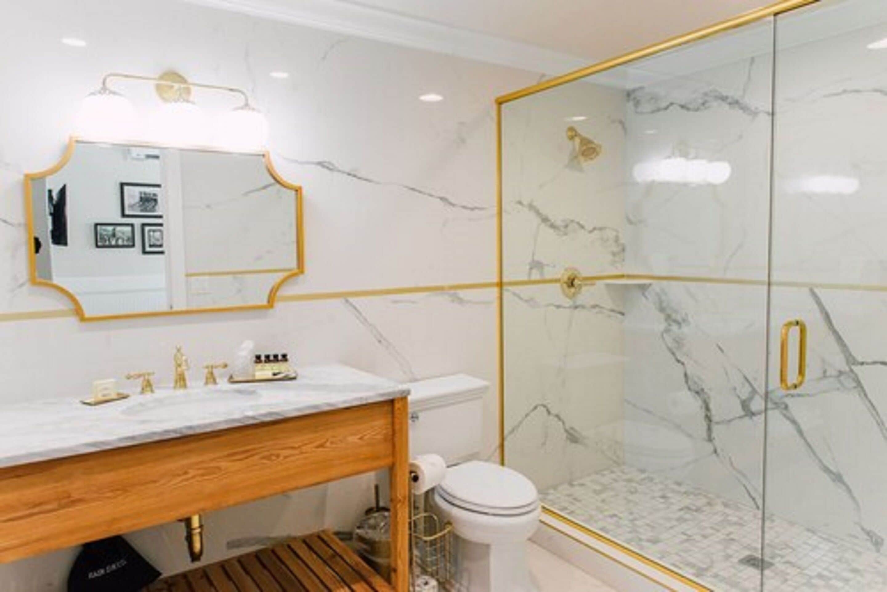 Une salle de bain avec un meuble-lavabo en marbre, une douche à parois de verre et des toilettes.