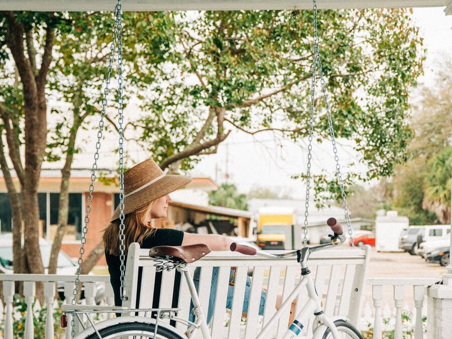 A white bicycle with a basket on a porch swing.