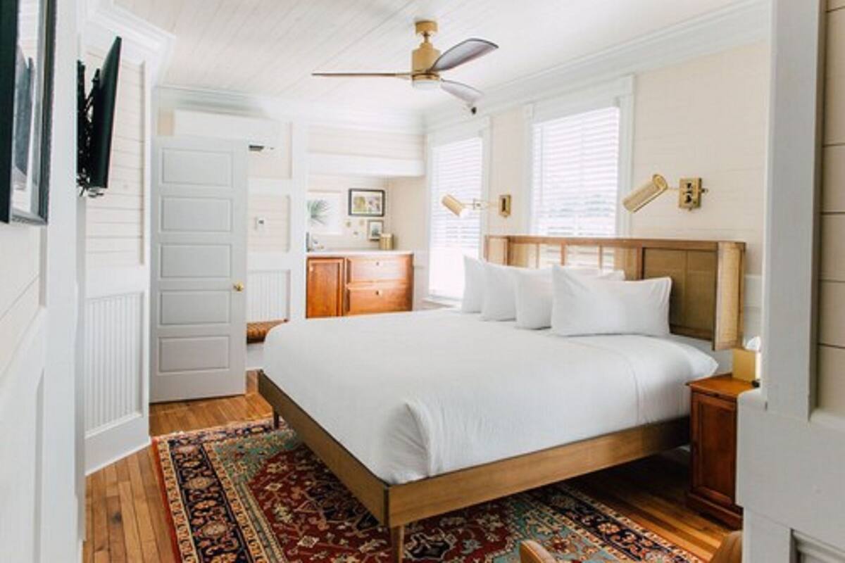 A bedroom with a wooden bed, a ceiling fan, a nightstand, and a window with blinds.