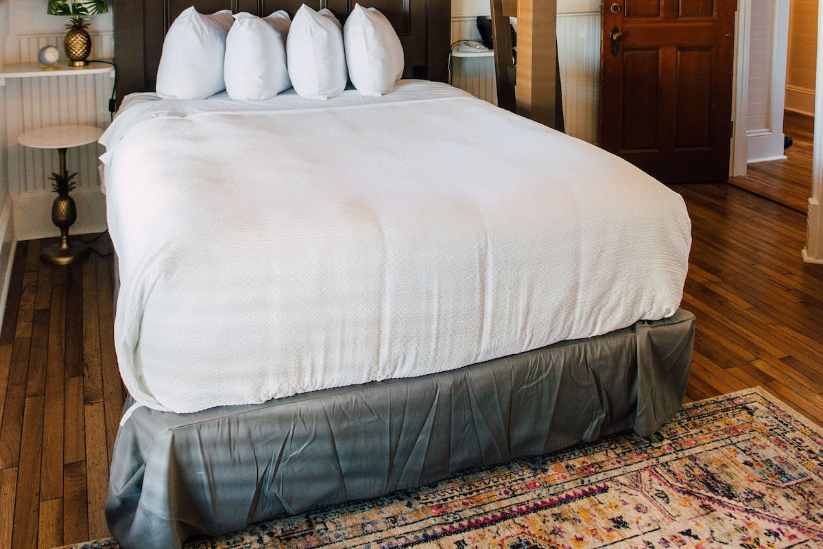 A large bed with a headboard, a ceiling fan, and a patterned rug.