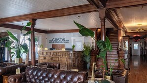 A lobby with a leather sofa, wooden reception desk, and large green plants. - Gibson Inn (Apalachicola)