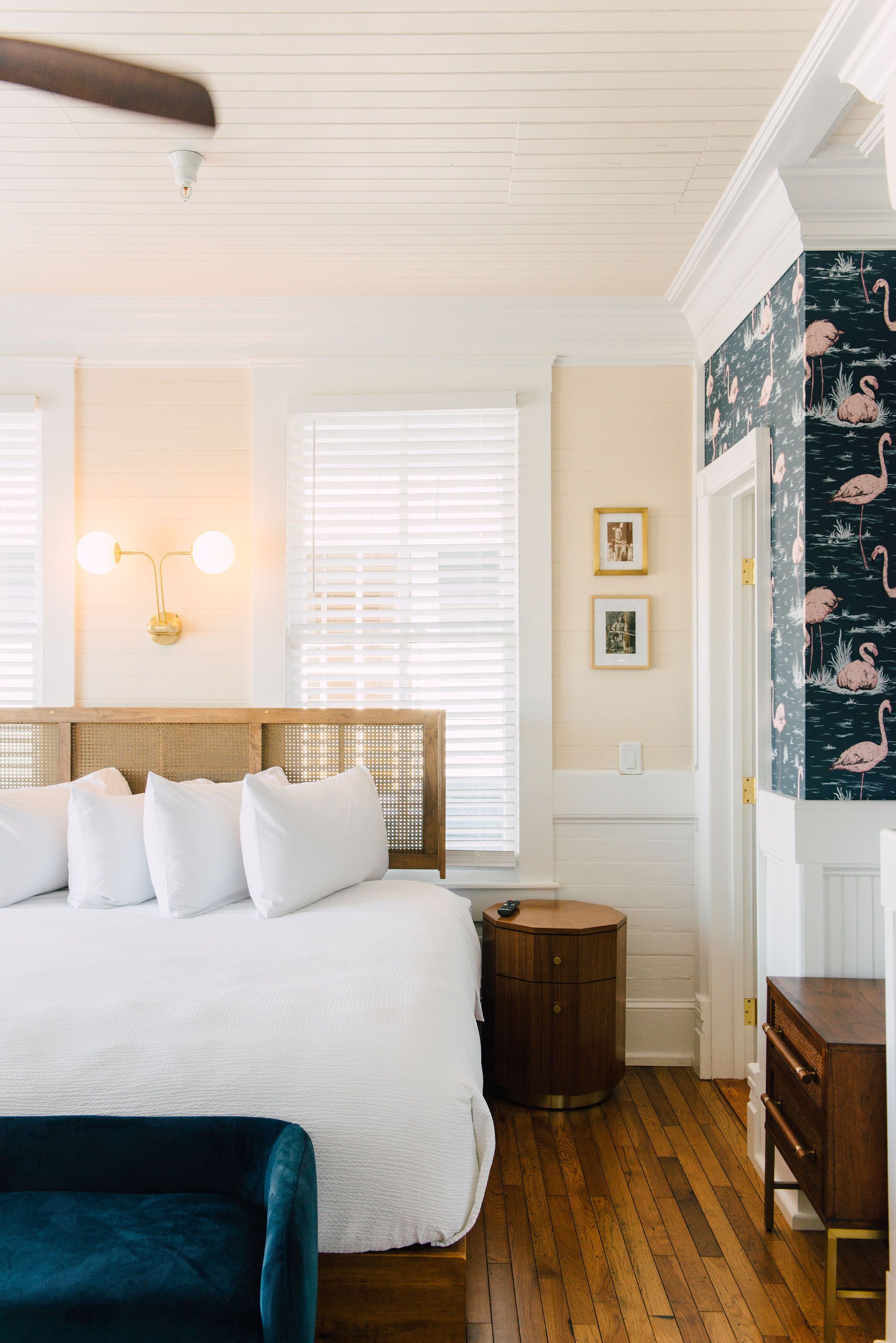 A bedroom with a large bed, wooden floor, a round nightstand, and a dresser.