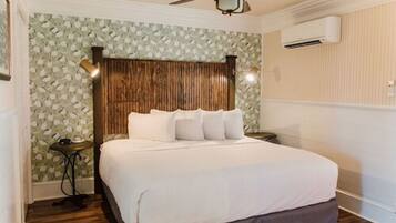 A bedroom with a wooden headboard, a bed with white bedding, a ceiling fan, and an air conditioning unit.