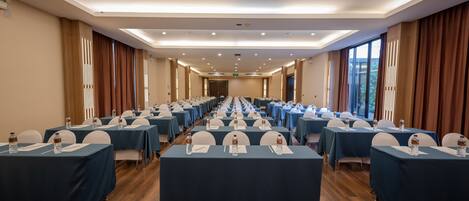 A conference room with rows of tables, each with water bottles and nameplates, and large windows on one side.
