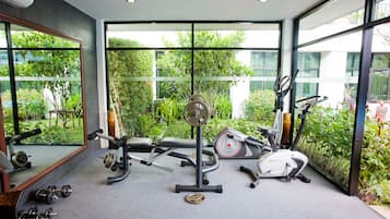 Ein Fitnessraum mit Trainingsgeräten, großen Fenstern und Blick auf Grünflächen.