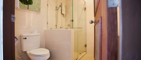 Un baño moderno con inodoro, lavamanos y ducha envuelta en vidrio.