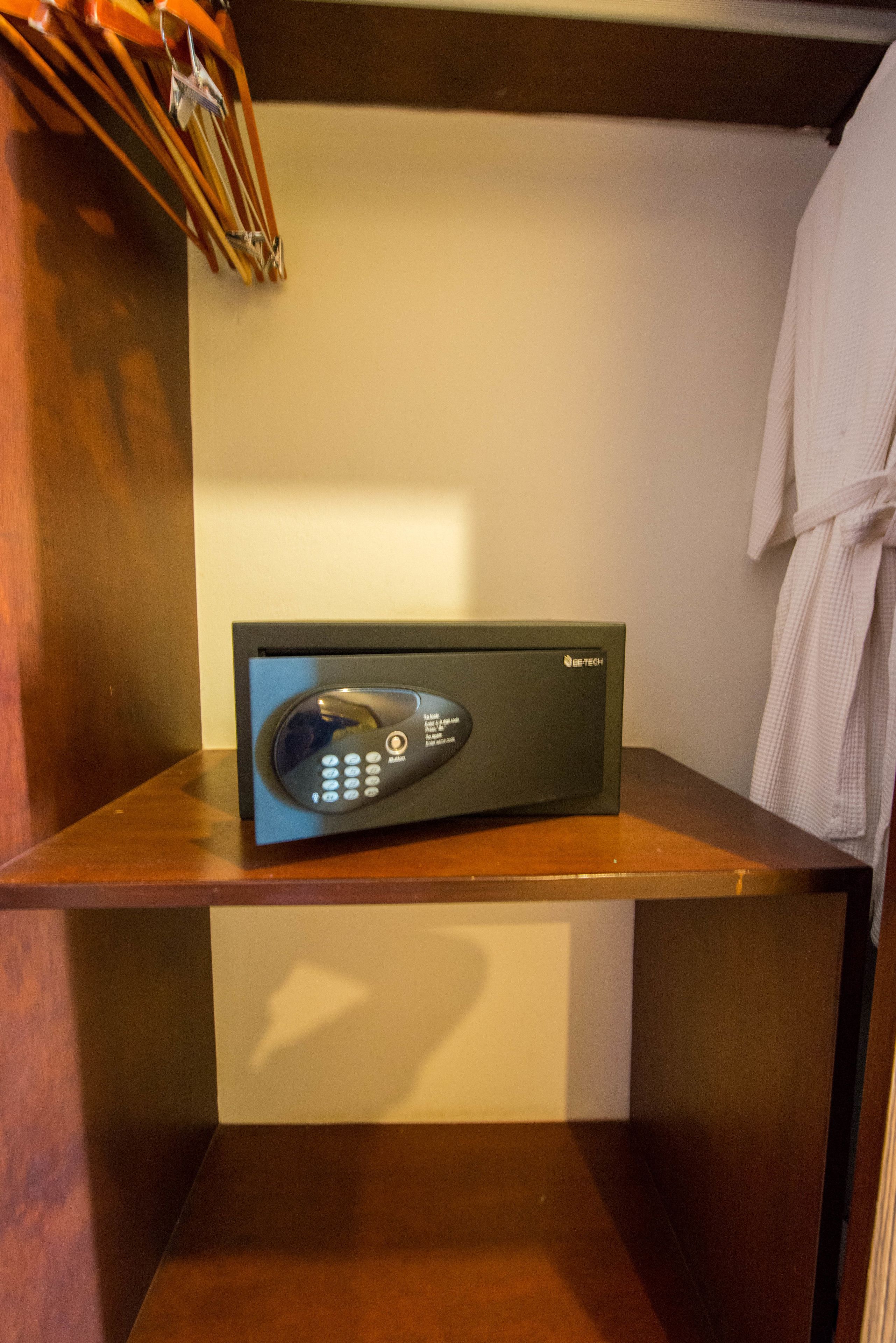 A room with a built-in microwave on a wooden counter, a robe hanging on the wall, and a wooden floor.