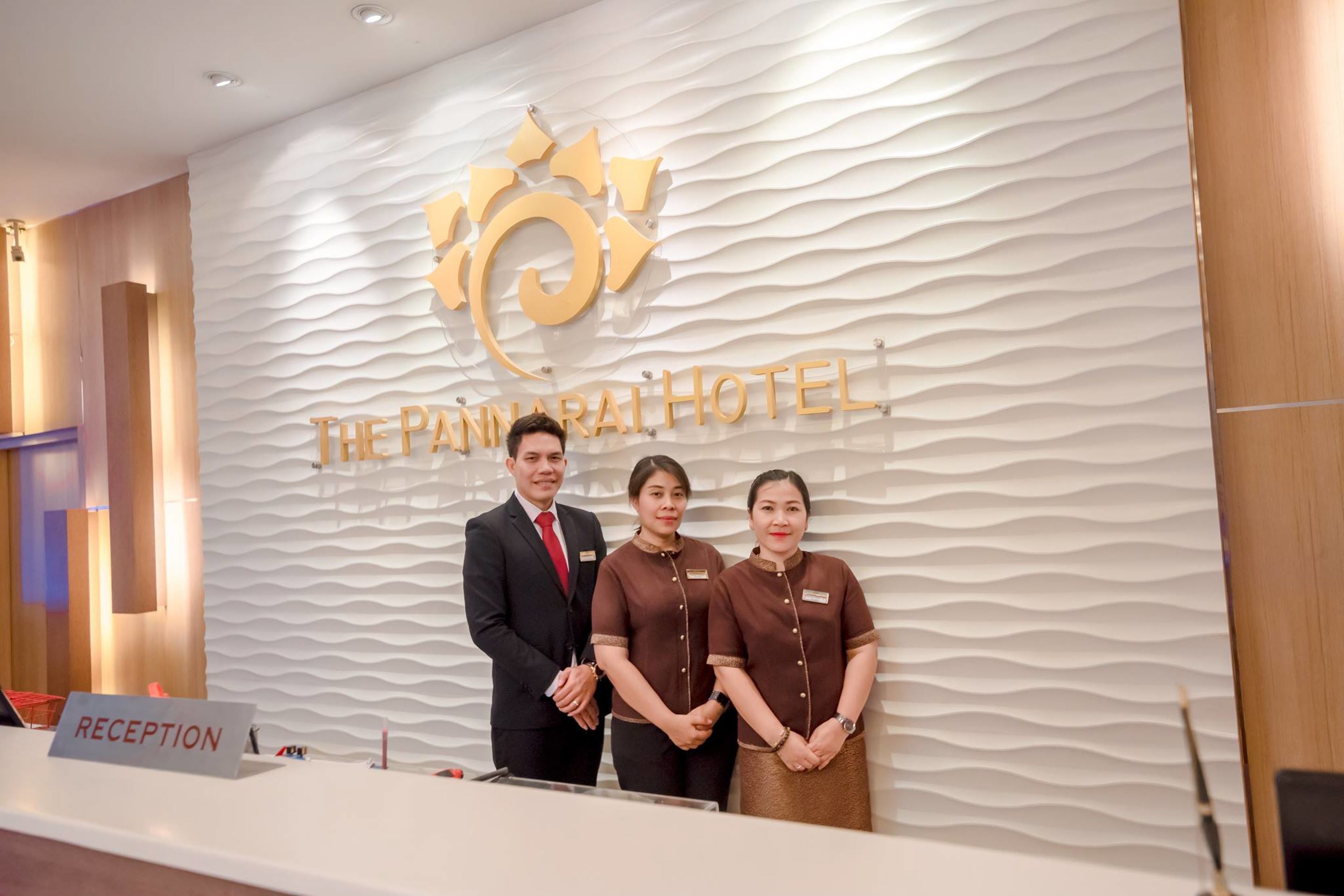 Een receptiebalie met een bordje met de tekst 'RECEPTION' en een logo voor 'The Panjara Hotel' erboven.