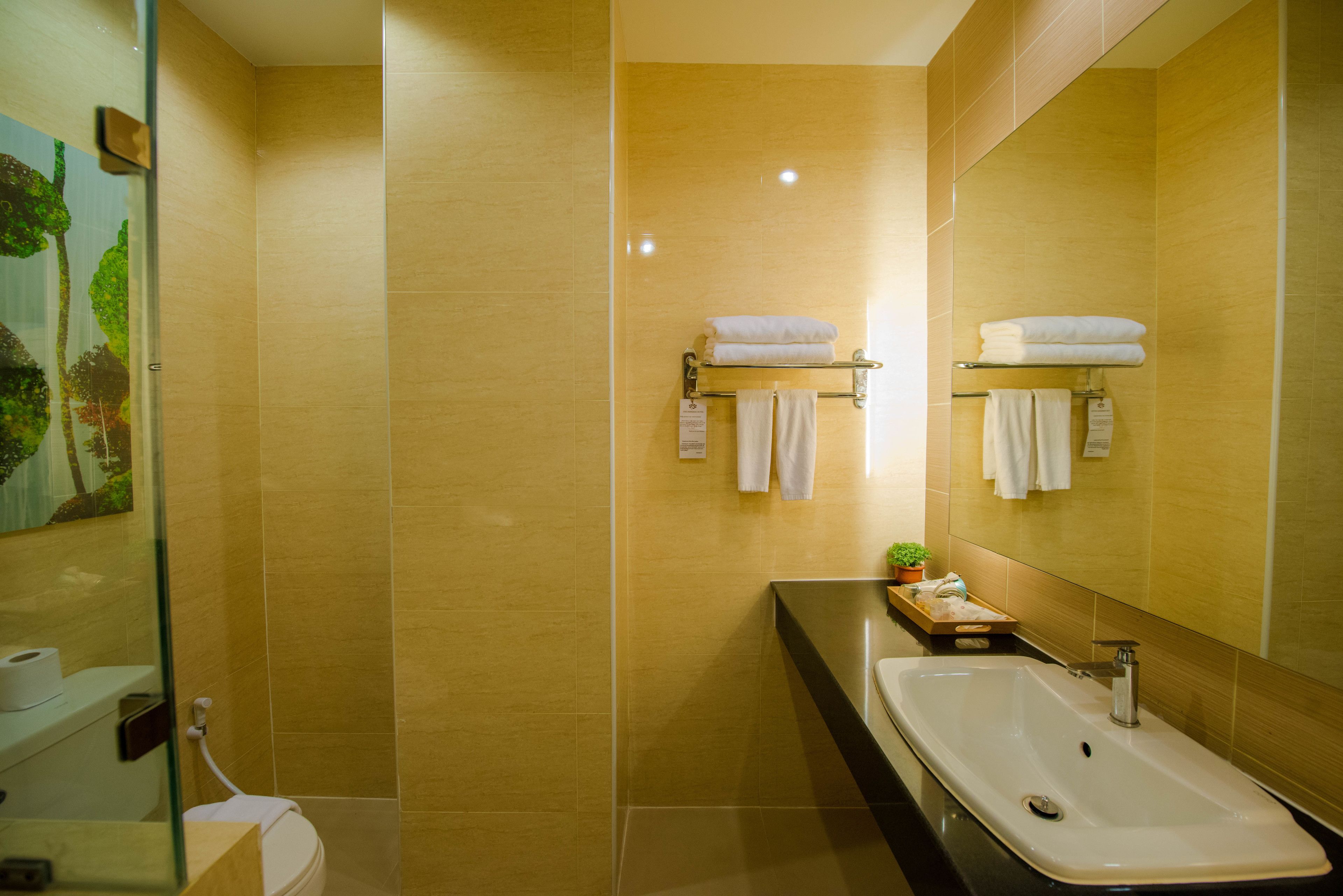Un baño moderno con un espejo grande, un lavamanos y dos toalleros.