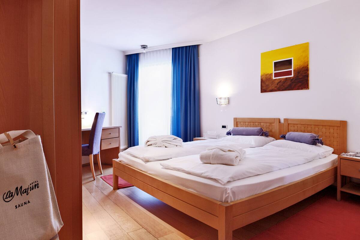A hotel room with a wooden bed, a desk, a chair, and a red carpet.