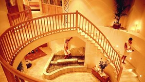 Eine geräumige, geschwungene Treppe mit Holzwandlauf zu einer niedrigeren Ebene.