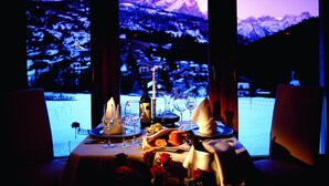 A table set for two with a mountain view, candles, wine glasses, and a bottle of wine. - La Majun (Badia)