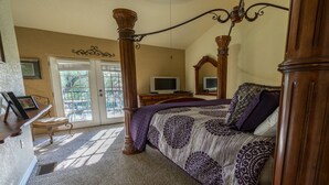 A bedroom with a four-poster bed, a television, and a large window.