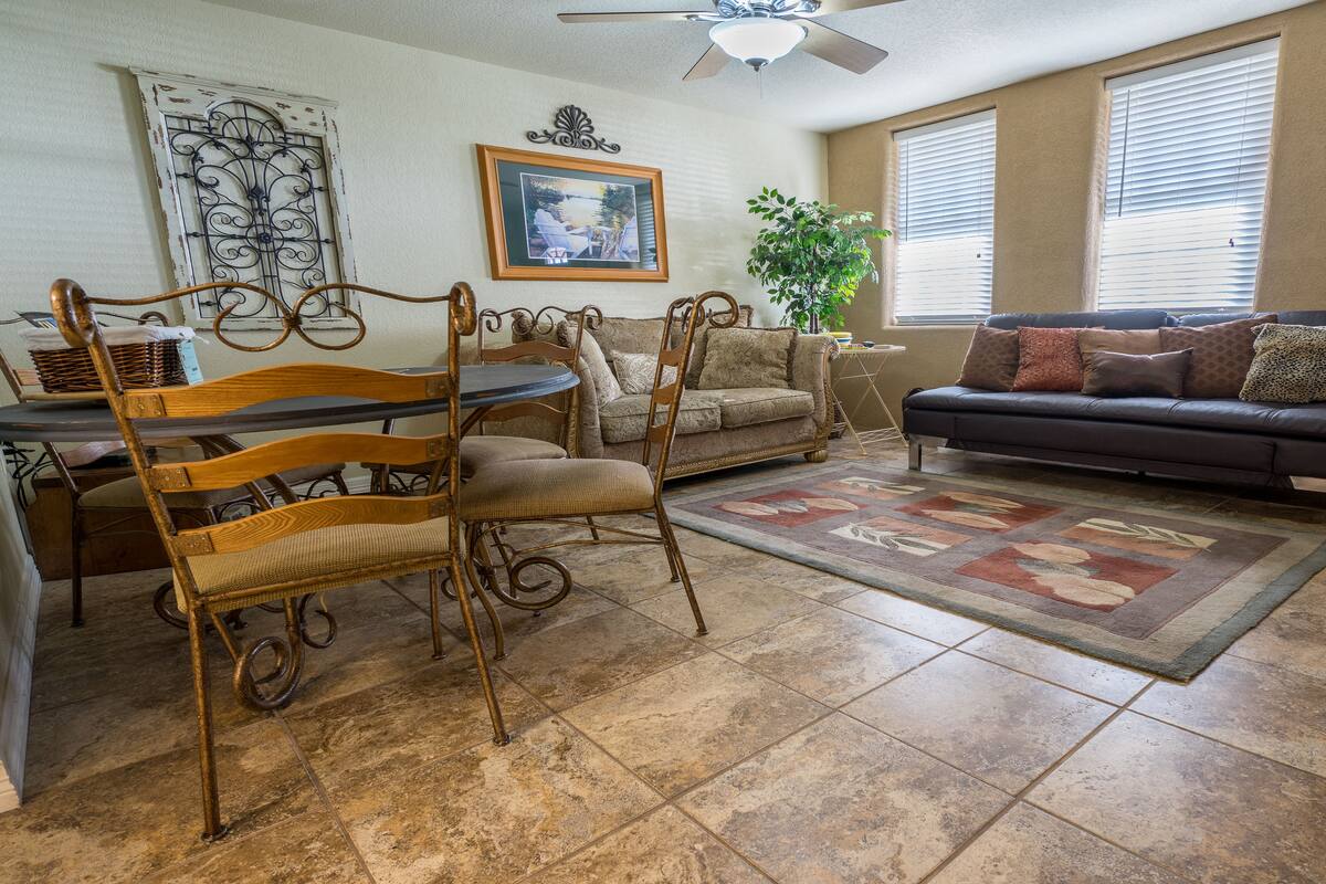 A living room with a dining area, a sofa, a coffee table, and a large window with blinds.