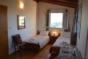 A room with two beds, a chair, a bedside table with a lamp, and a framed picture on the wall. - Villa Galini (Hersonissos)