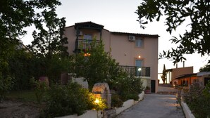 A two-story building with a balcony, a stone archway, and a pathway leading to the entrance.