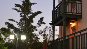 A building with a balcony, a potted plant, and a street lamp.