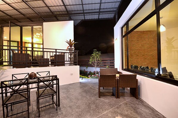 Un patio al aire libre con una mesa de comedor y sillas, una planta pequeña y vistas al cielo nocturno.