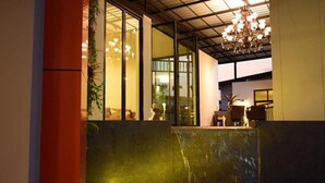 A modern interior with a water feature, large windows, and a chandelier. - Good Home Udonthani (Udon Thani)