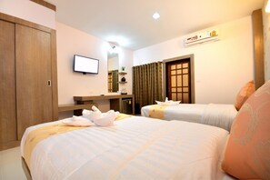 A hotel room with two beds, a TV, a desk with a computer, and a wardrobe. - Good Home Udonthani (Udon Thani)