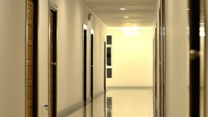 A long, well-lit hallway with doors on both sides, leading to a bright room at the end. - Good Home Udonthani (Udon Thani)