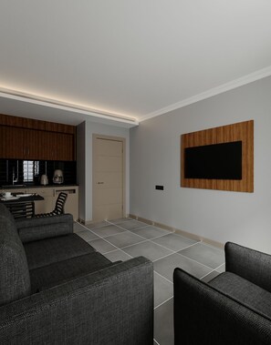 Una sala de estar moderna con sofá, televisión montada en la pared y zona de cocina con armarios y electrodomésticos.