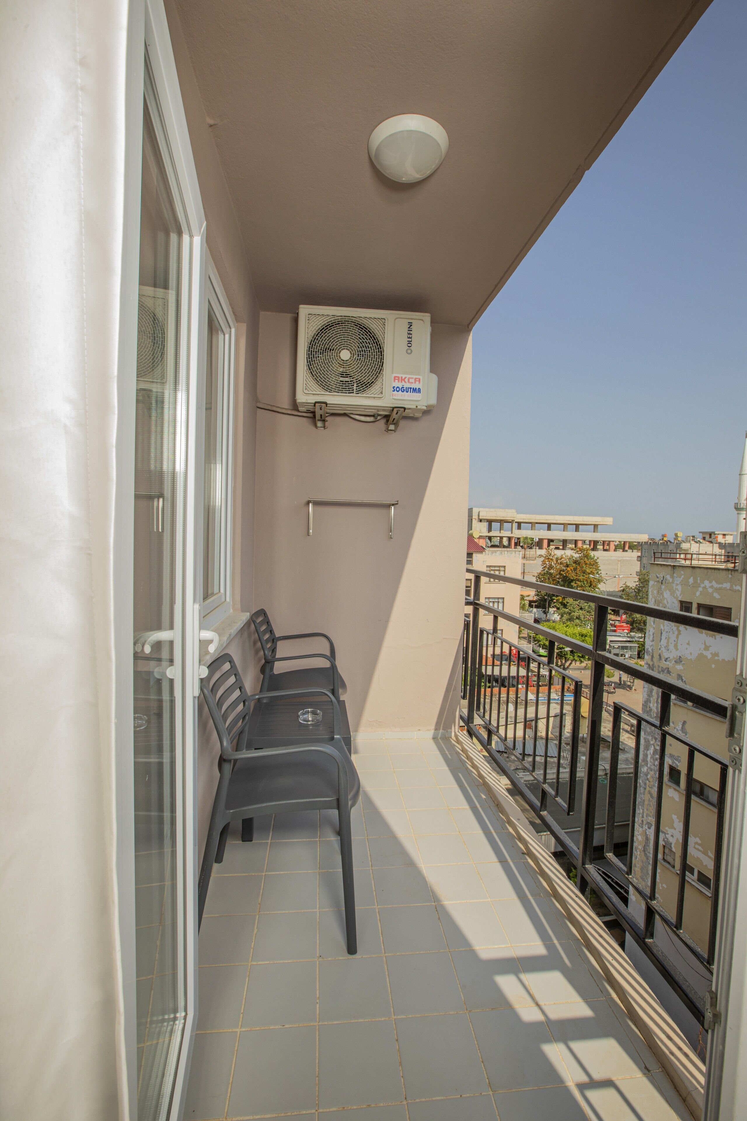A balcony with a ceiling fan, a window with a curtain, and a view of buildings.