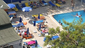 Un espace aménagé au bord de la piscine, avec des chaises longues et des parasols, une piscine et un coin salon abrité.