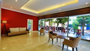 Un grand espace intérieur avec un mur rouge, un canapé et plusieurs fauteuils.