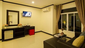 Uma sala de estar moderna com um sofá preto, uma mesinha de centro, uma TV fixada na parede e uma janela com cortinas.